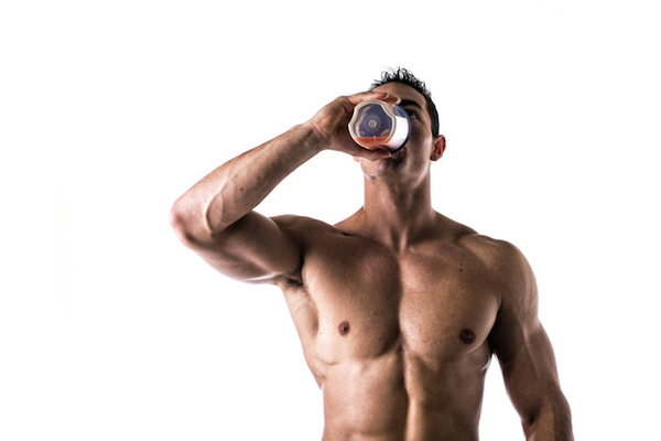 Muscular shirtless male bodybuilder drinking protein shake from blender. Isolated on white, looking up